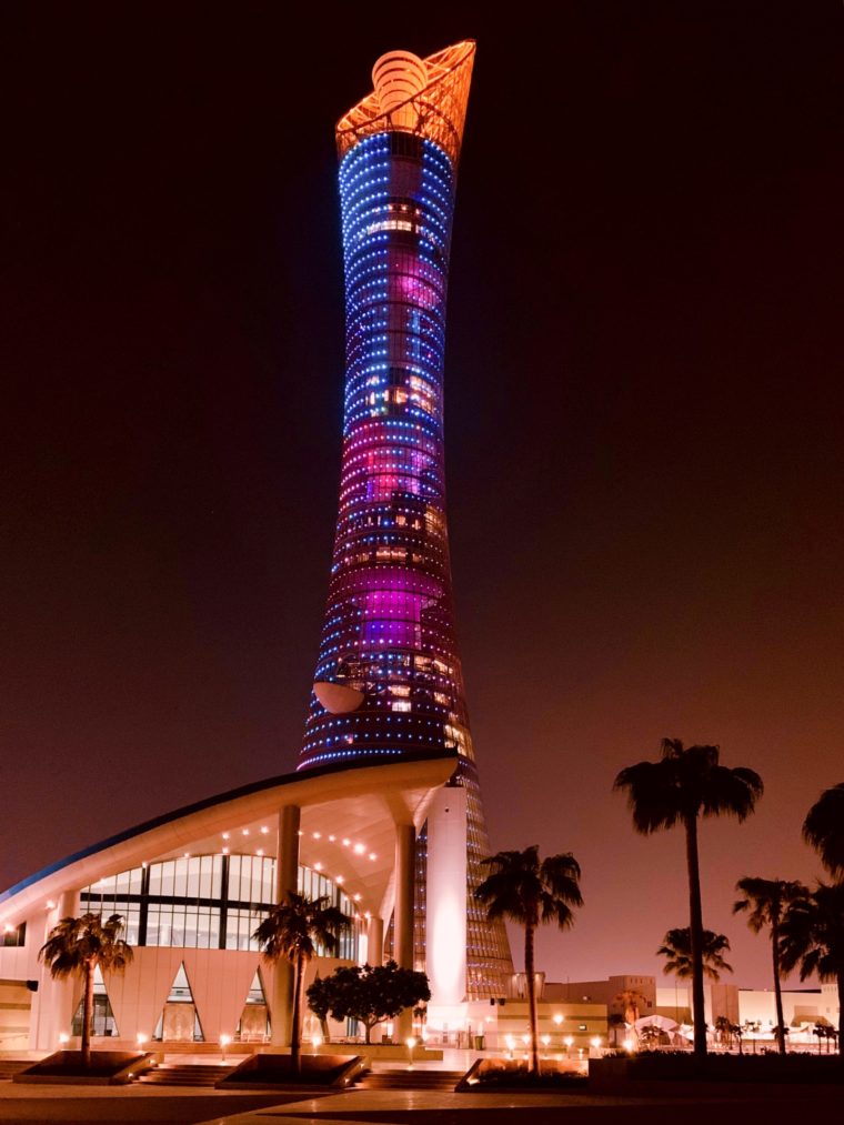 A colorful tall building at night with palm trees
