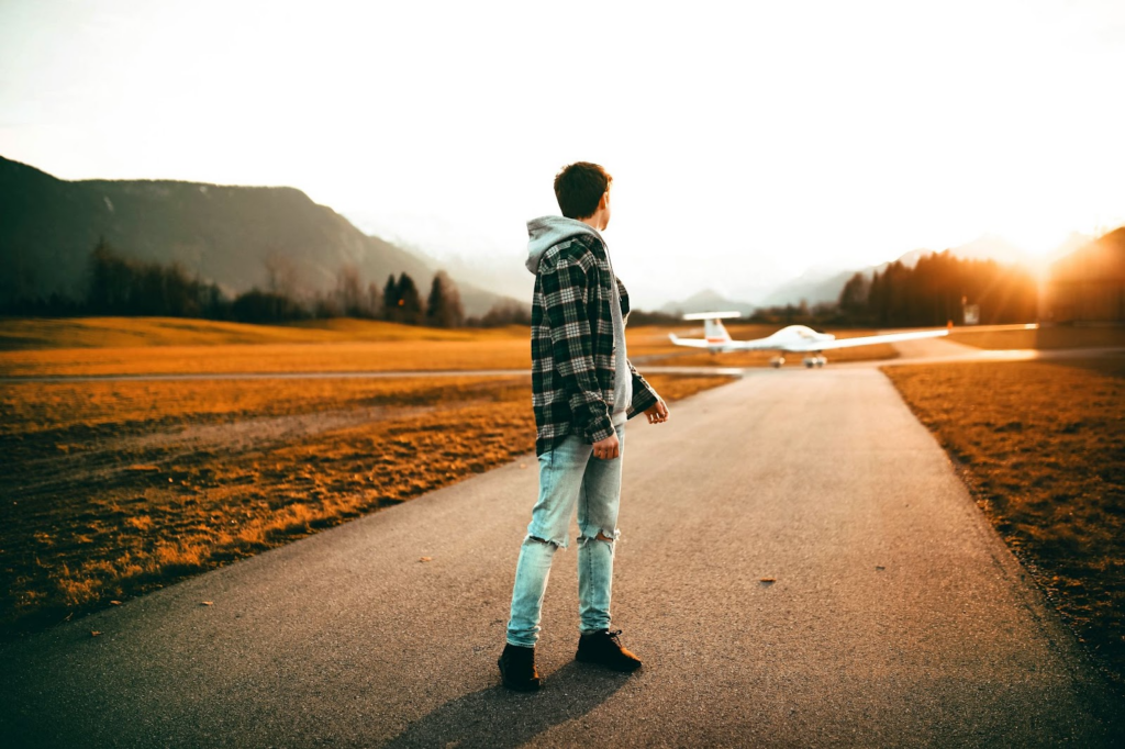 Young kid standing in the runway with a plane ahead of him