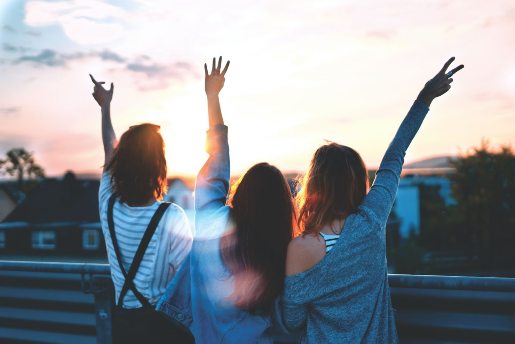 Three young girls waving at the sky