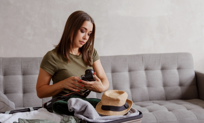 Woman looking at her camera while packing a suitcase