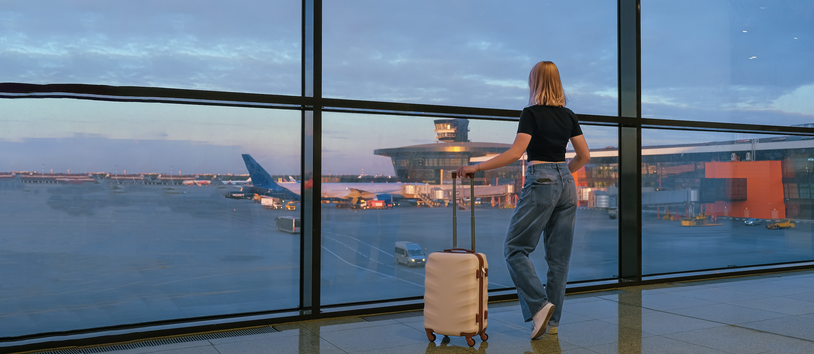 Woman looking at planes at an airport with a suitcase